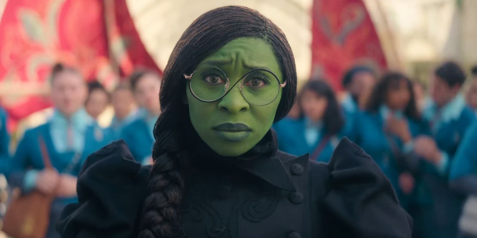 Cynthia Erivo as Elphaba arriving in Emerald City, wearing glasses and looking concerned in Wicked.