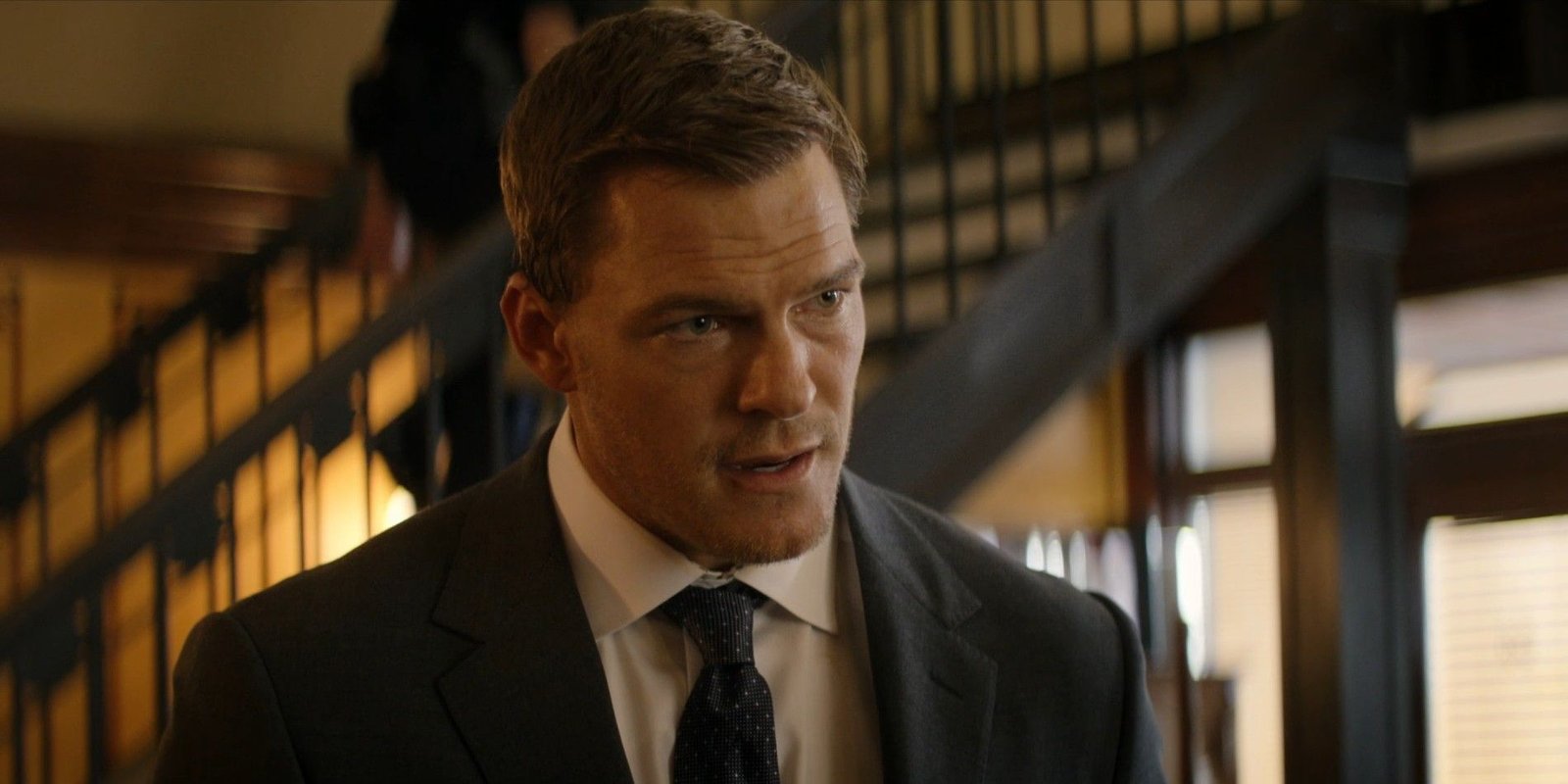 Alan Ritchson wearing a suit as Reacher.