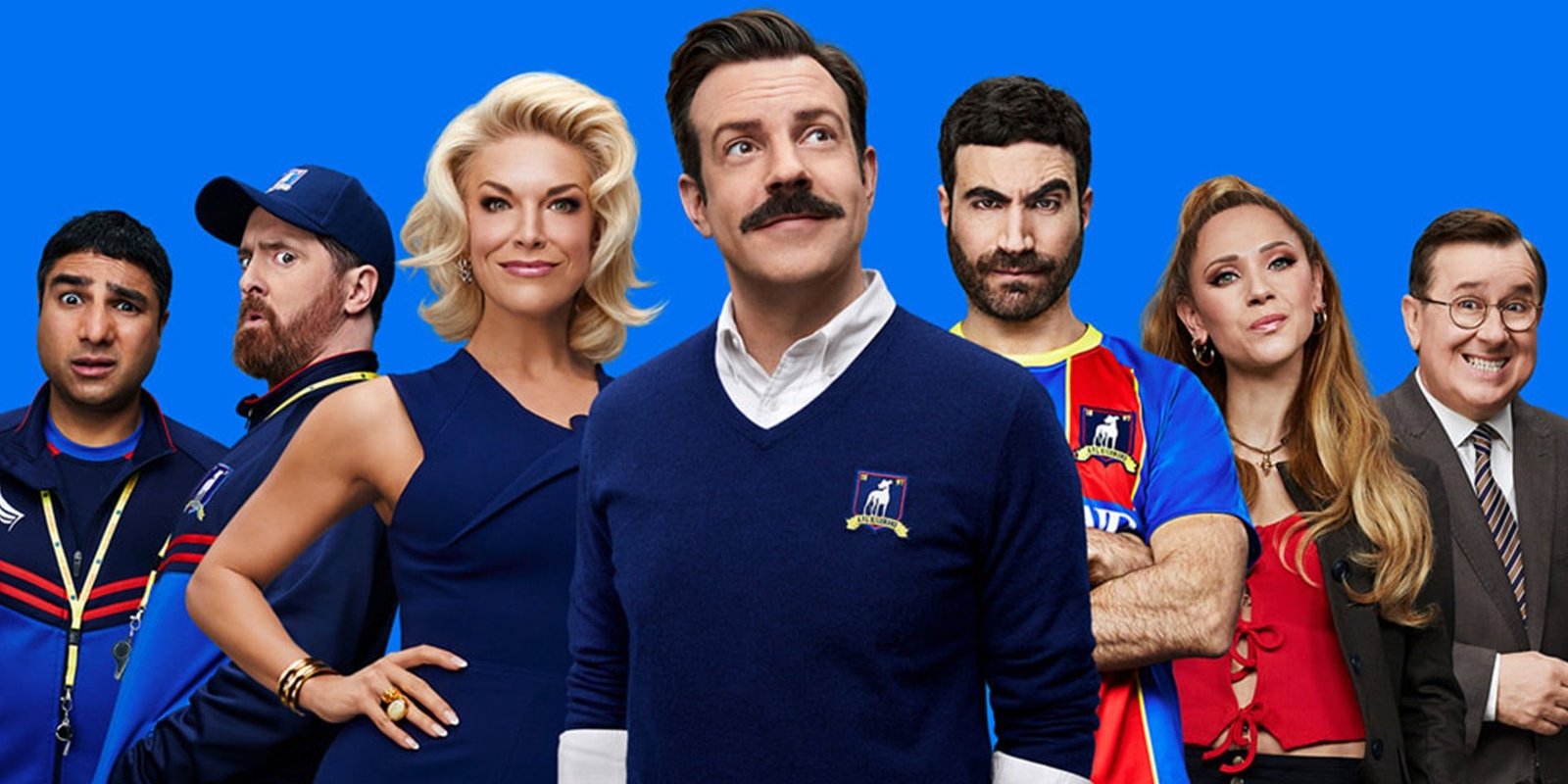 The cast of Ted Lasso pose together on a poster for the show featuring a blue background